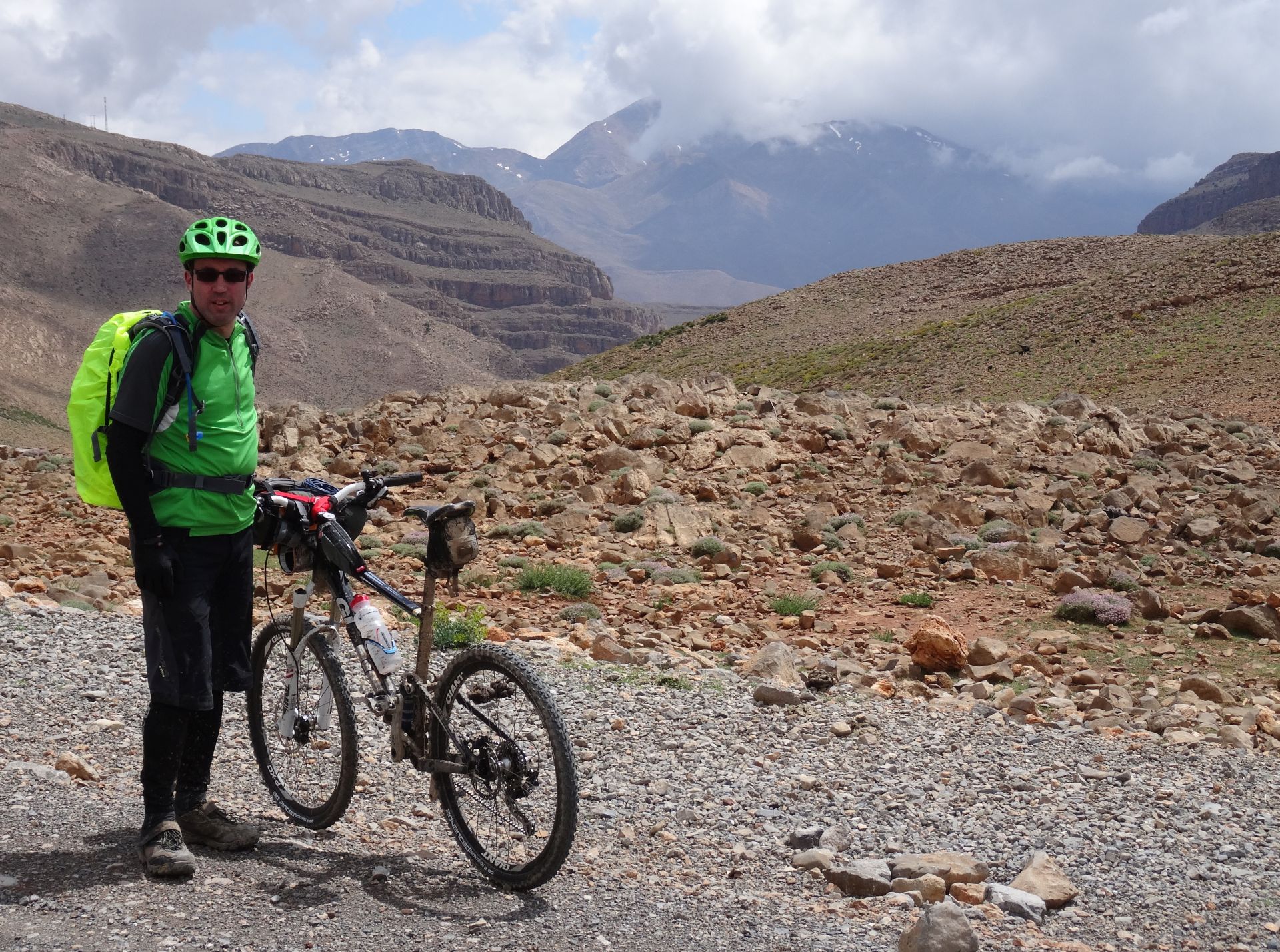 Day 1 - Mountain (Bike) Man, Steve. On the climb up the Tizi-n-Ouanergui pass (8,238 ft), before dropping into Anergui. Jbel Leqroun in cloud, on horizon. © Steve Woodward