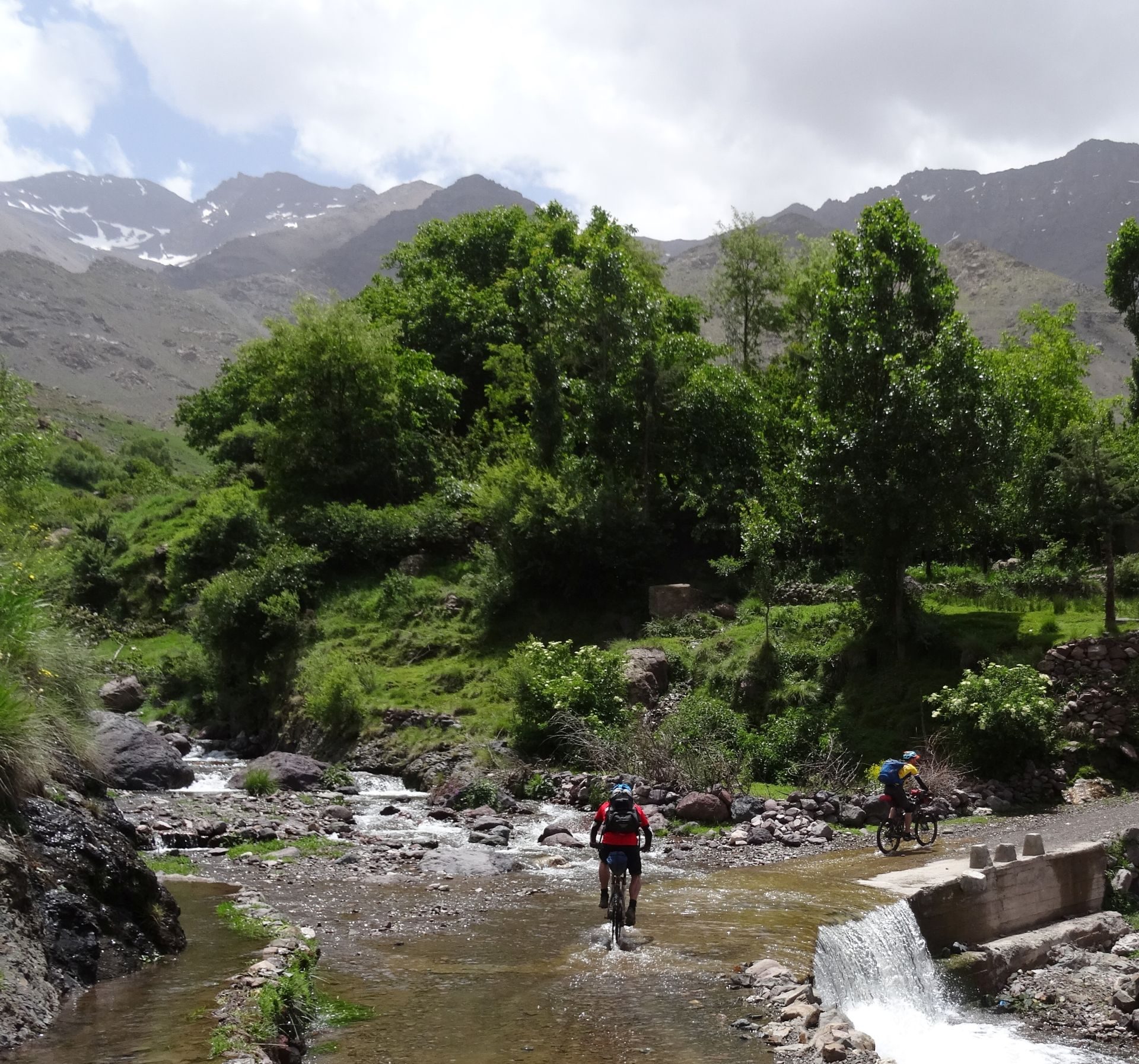 Day 8 - Splish Splash Splosh, & nearly Bish Bash Bosh! Wheel dip in the Assif Imenane river, leaving Tizi-n-Tacheddirt, en route to Imlil, before our final day of riding, tomorrow. Bou Iguenouane (12,736 ft) on left, Jbel Aksoual (12,828 ft) right - form part of a 10-mile ridge traverse for another time! © Steve Woodward