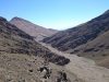 Day 6 - The moon AKA the descent from the Tizi-n-Tamadla pass & the dried-up river bed across which we need to ride (boulders!) Looking west, with lake Tamda in the distance, & flanks of Jbel-n-Anghomar on the right.  © Shaun Grey
