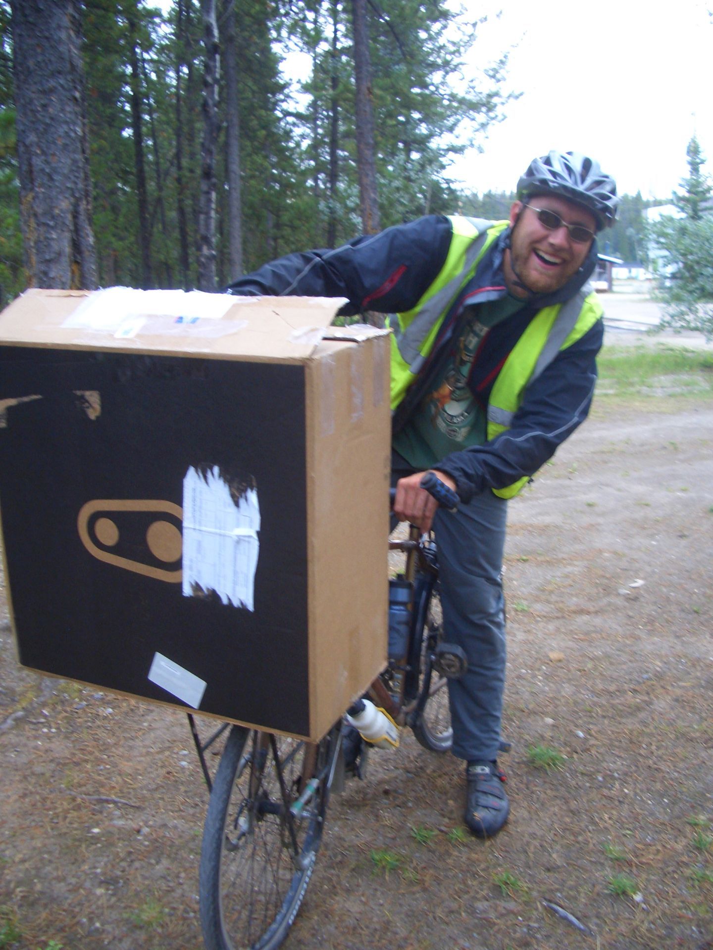 Watson Lake, YT, Canada - Me on Ward`s bike having just picked up 2 new wheels (in box) from bus station 2 miles up road...did well not to crash on way back I thought! (pic courtesy of the Budwegs)
